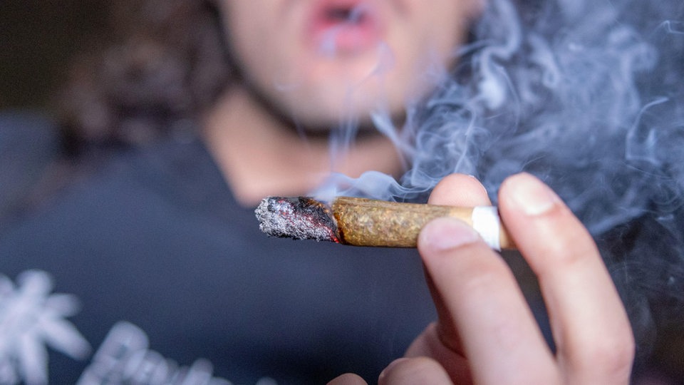 Ein junger Mann raucht einen Joint (Symbolfoto)
